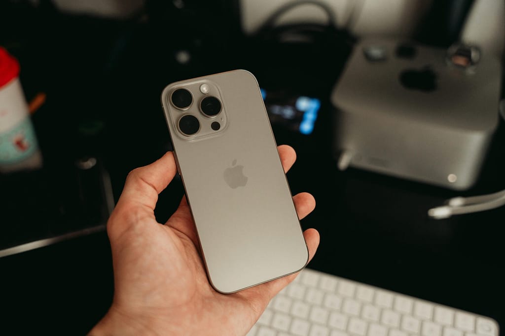 A hand holding a sleek smartphone in a tech-savvy office environment, showcasing its design.